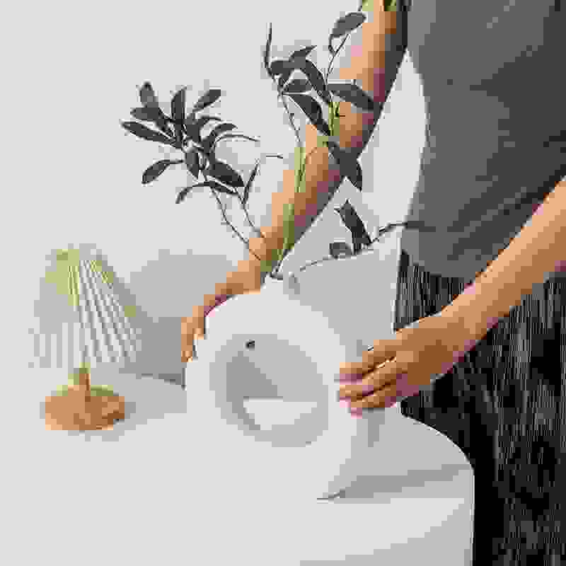 NordicBloom™ Elegant Flower Vase Decorative Display in white, held by a person, styled with green foliage for living room elegance.